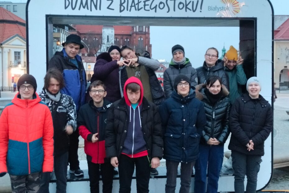 Grupa uczniów pozujących do fotografii w tle rama z napisem: Dumni z Białegostoku