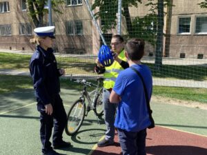 Policjantka instruuje uczestnika konkursu o zasadach używania kamizelki odblaskowej i kasku rowerowego.