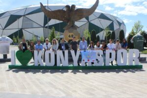 Grupa uczniów i nauczycieli przy stadionie piłkarskim, przy napisie "I love Konyaspor"