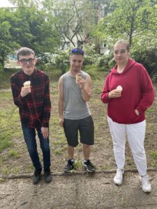 trójka wychowanków pozuje do zdjęcia trzymając w rękach lody