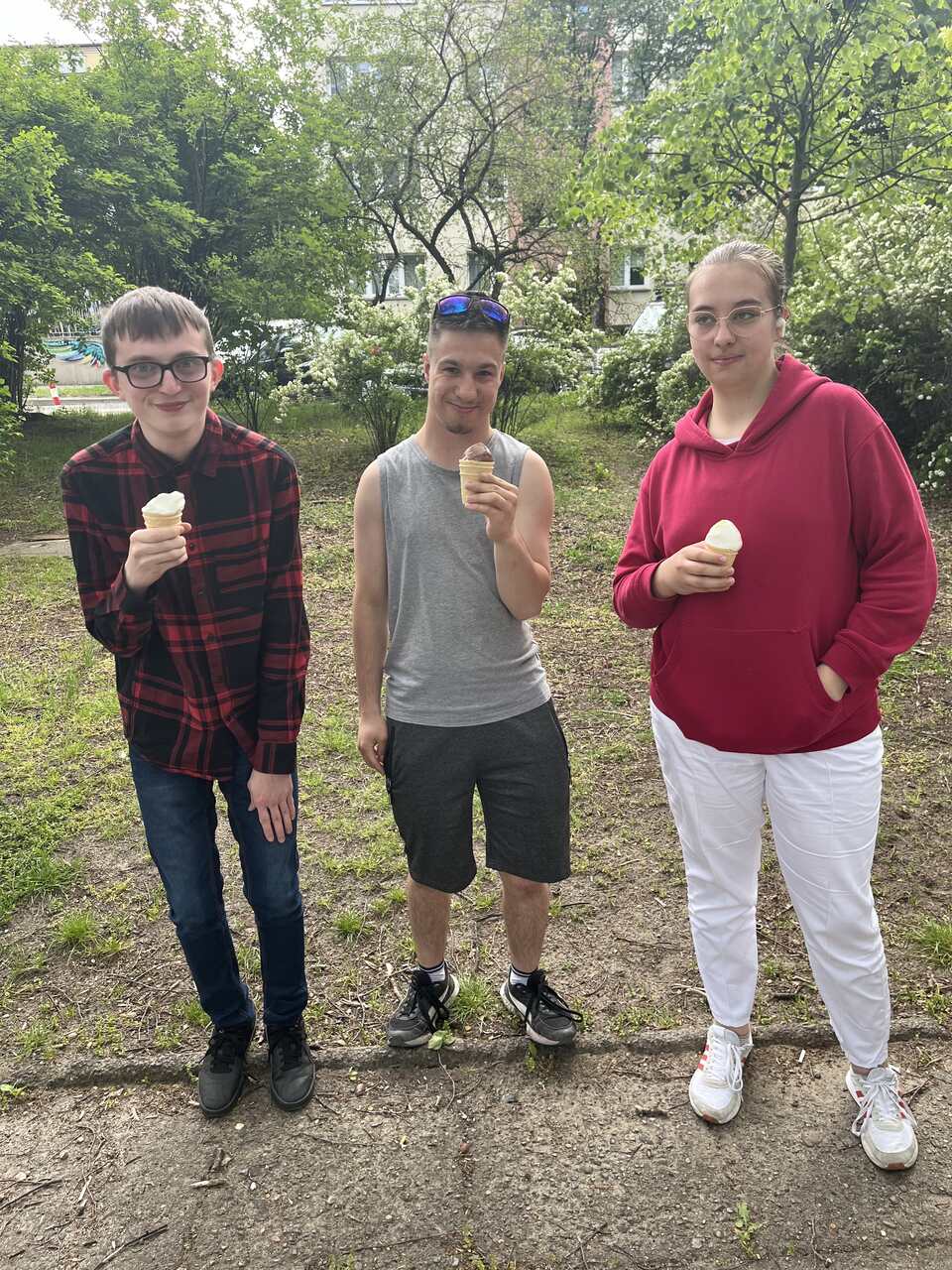 trójka wychowanków pozuje do zdjęcia trzymając w rękach lody