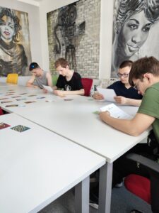 Chłopcy siedzą przy stołach i czytają instrukcje do zadania.