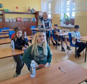 Zawodnicy piszą Test z wiedzy o ruchu drogowym w sali dydaktycznej.