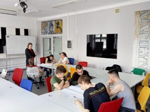 Uczniowie w dwóch oddzielnych grupach rysują na dużych arkuszach papieru plan działania.