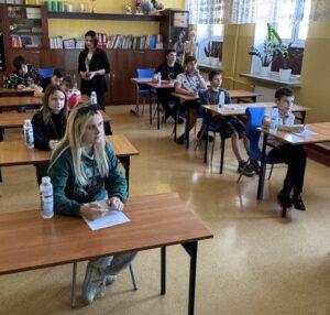 Zawodnicy piszący test z wiedzy o ruchu drogowym w sali dydaktycznej,