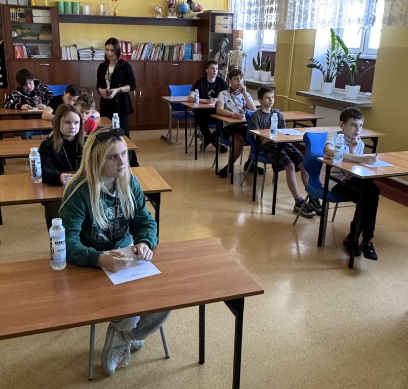 Zawodnicy piszący test z wiedzy o ruchu drogowym w sali dydaktycznej,