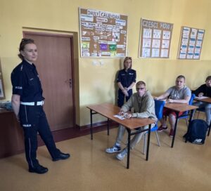 Panie Policjantki obserwujące zawodników piszących test w sali dydaktycznej,