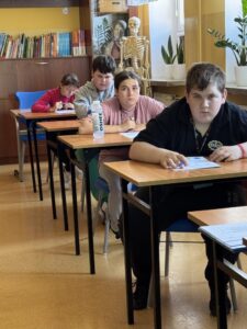 Zawodnicy piszący Test z wiedzy o ruchu drogowym w Sali dydaktycznej,