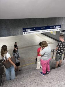 Wychowankowie wraz z panią Kingą stoją przy tablicach oznaczających perony na dworcu PKS.