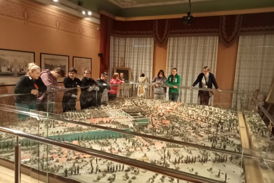 Młodzież wraz z wychowawcą patrzą na wielką makietę miasta w muzeum.