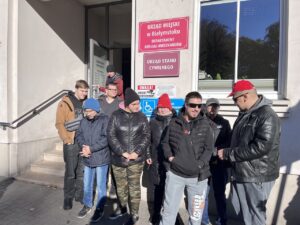 Młodzież stoi przed budynkiem Urzędu Miejskiego.
