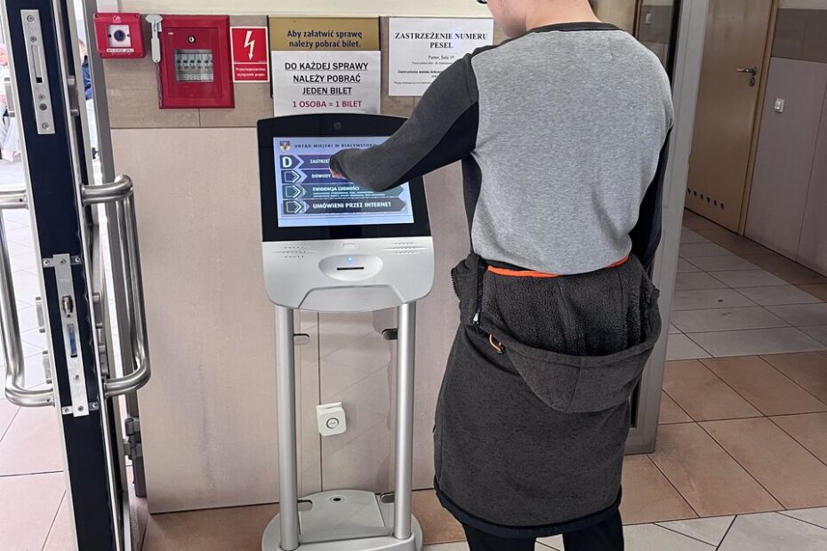 Wychowanek stoi przy monitorze, gdzie wybiera, którą sprawę urzędową chce załatwić.