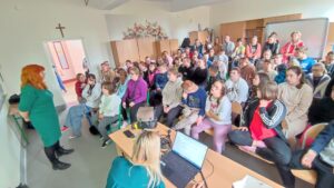 Grupa uczniów słuchających prelekcji o przeciwdziałaniu przemocy rówieśniczej