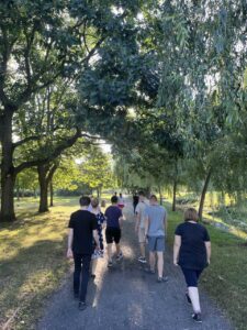 Młodzież z wychowawcą spaceruje ścieżką w parku.