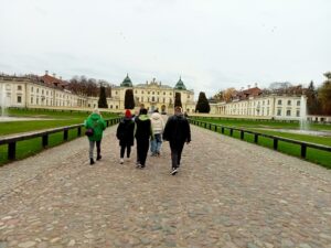 Wychowankowie wraz z wychowawcą idą przez Dziedziniec Wstępny w stronę Pałacu Branickich.