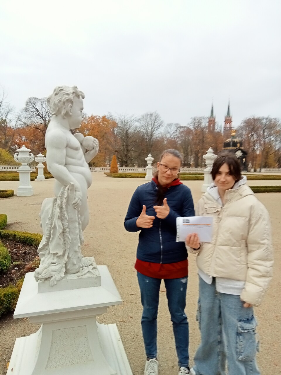 
Dwie wychowanki stoją przy rzeźbie przedstawiającej małego chłopca.
