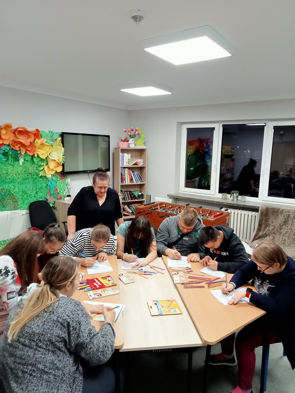 Wychowawczyni p. Jola obserwuje młodzież rysującą kolorami emocje
