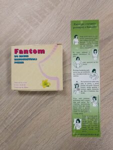 Zdj. 1 na stole leży pudełko, w którym zapakowany jest fantom piersi, obok leży ulotka z instrukcją jak samemu badać piersi.
