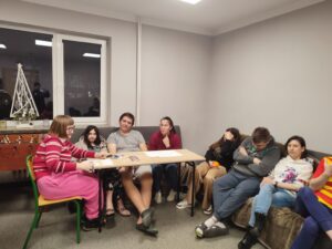 Grupa uczestników siedzi w sali podczas zajęć oglądając prezentację.