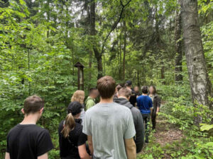 Zd.3 Młodzież spaceruje po ścieżce edukacyjnej w lesie i słucha informacji przekazywanych przez przewodnika o roślinach i zwierzętach .