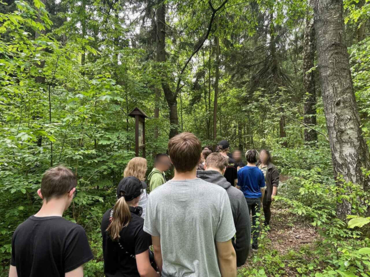 Zd.3 Młodzież spaceruje po ścieżce edukacyjnej w lesie i słucha informacji przekazywanych przez przewodnika o roślinach i zwierzętach .