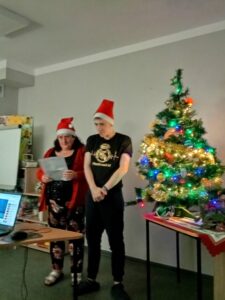 Zdjęcie przedstawia wychowawcę wspierającego uczestnika podczas prezentacji.