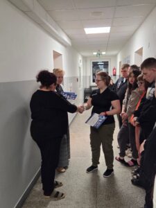 Wychowankowie stoją na korytarzu i czekają na ogłoszenie wyników przez wychowawców.
