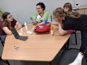 Wychowawczyni tłumaczy wychowankom zasady udzielania pierwszej pomocy. 