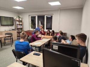 1. Wychowawczyni rozdaje siedzącej wokół stołu młodzieży materiały do ćwiczeń
