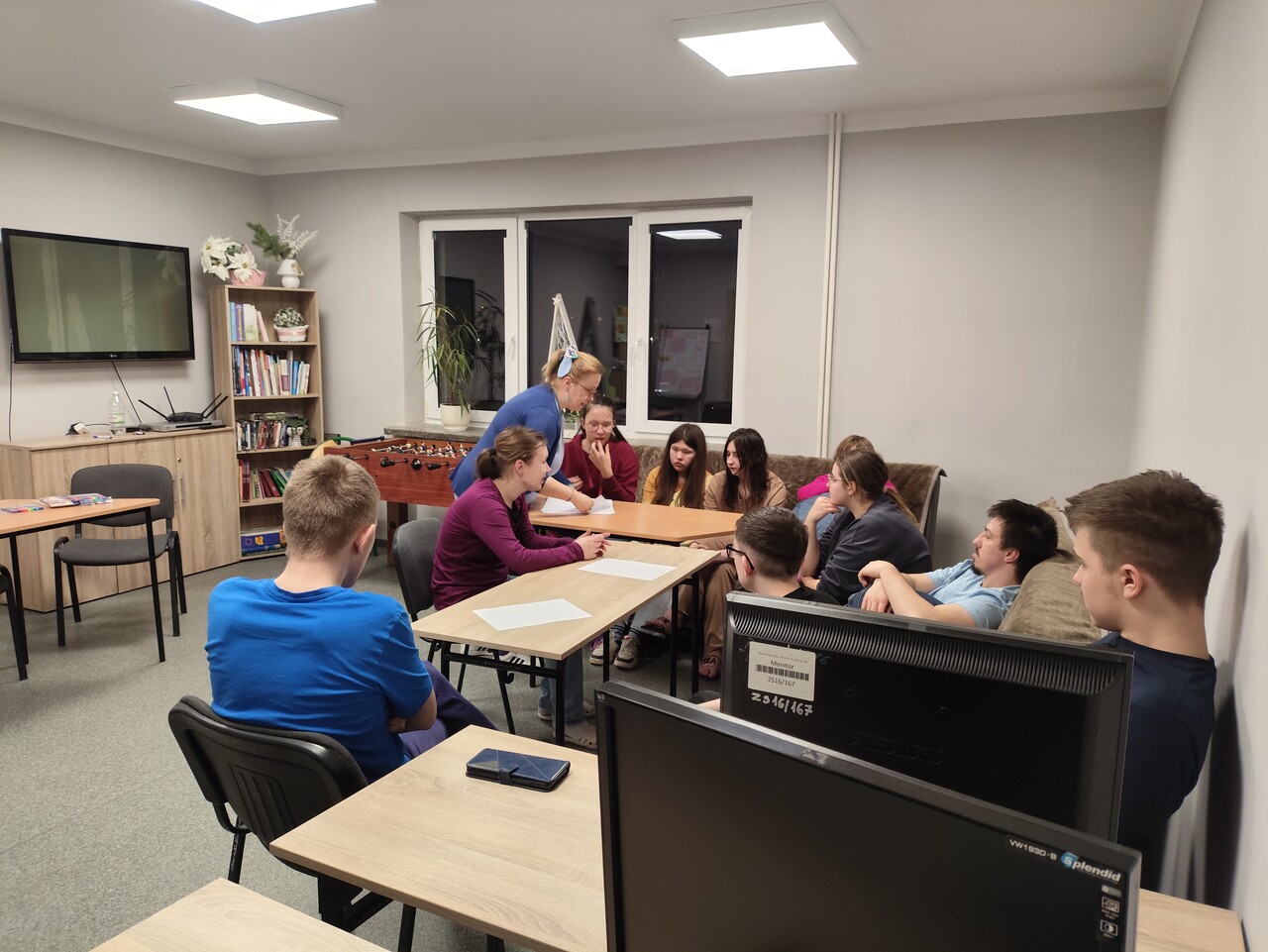 1. Wychowawczyni rozdaje siedzącej wokół stołu młodzieży materiały do ćwiczeń
