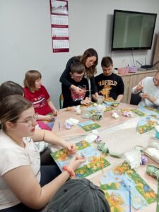 3 zdjęcie. Wychowawczyni pomaga wychowankom w dekoracji.
