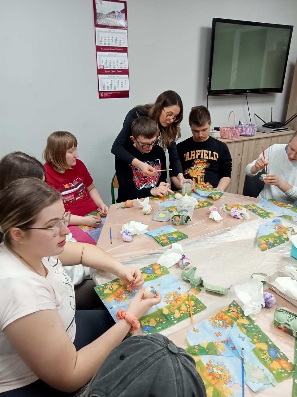 3 zdjęcie. Wychowawczyni pomaga wychowankom w dekoracji.
