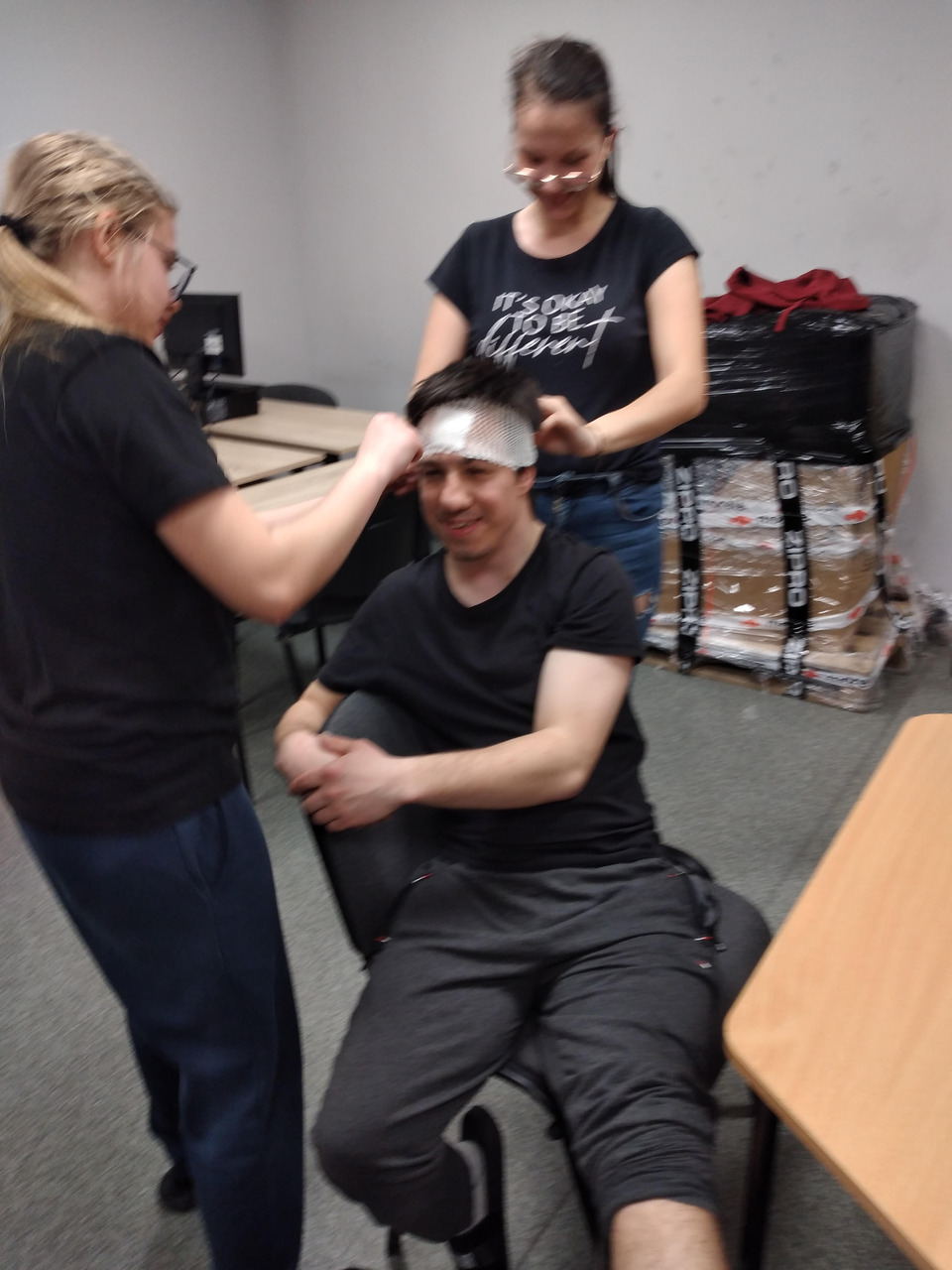 Koleżanki zakładają koledze opatrunek na ranę głowy.