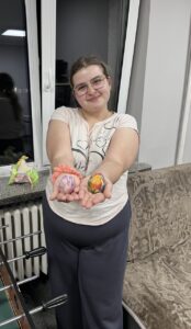 4 zdjęcie. Wychowanka prezentuje udekorowane przez siebie jajka.
