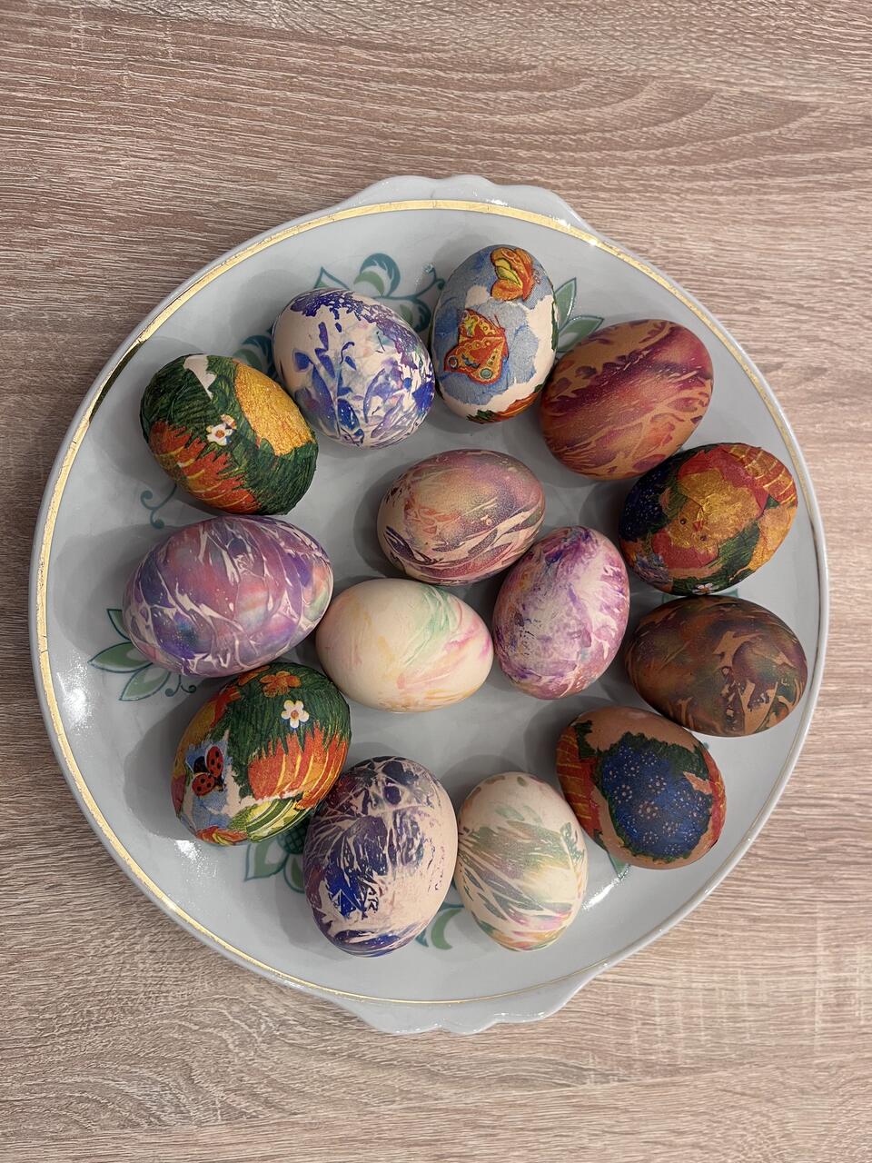 5 zdjęcie. Na stole stoi talerz z udekorowanymi przez młodzież jajkami.