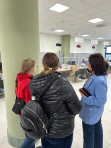 Zdj. 2
Grupa uczniów słucha wyjaśnień dotyczących pracy urzędników i obsługi interesantów w sali obsługi klienta ZUS. Pani w niebieskiej marynarce w ciekawy sposób prezentuje funkcjonowanie urzędu.
