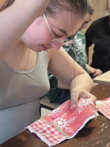 Zd.2
Dziewczynka igła z nitką zszywa materiał.