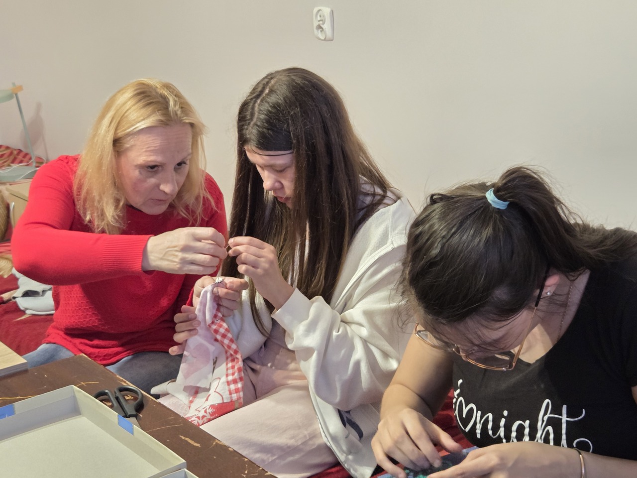 Zd.5
Wychowawczyni pokazuje dziewczynce, jak prawidłowo wykonać zszycie materiału.