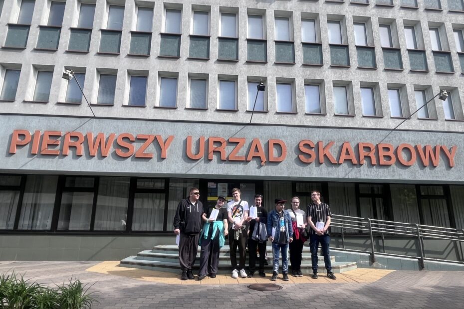 Zdj. 1 Wychowankowie stoją przed budynkiem Urzędu Skarbowego.