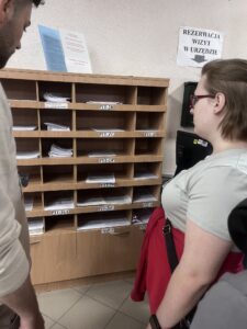 Zdj. 5 Pracownik urzędu pokazuje wychowankom półkę z dostępnymi drukami do wypełnienia.